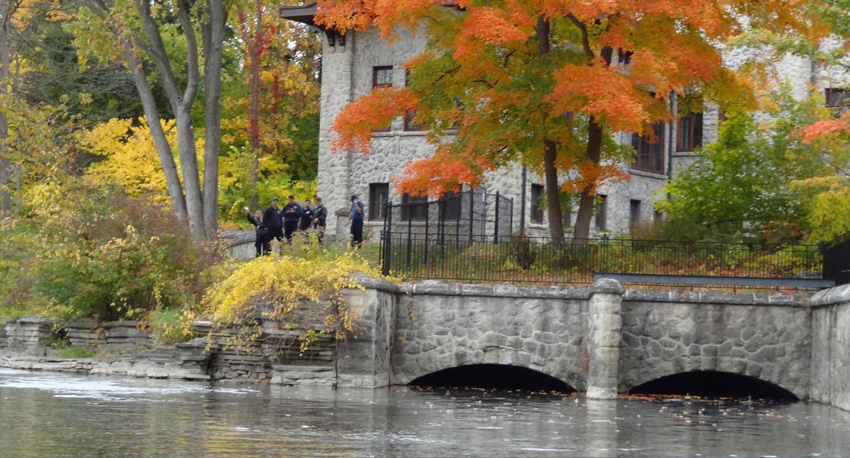 Beautiful fall color of trees and people waving from a home along the Rouge River, river view