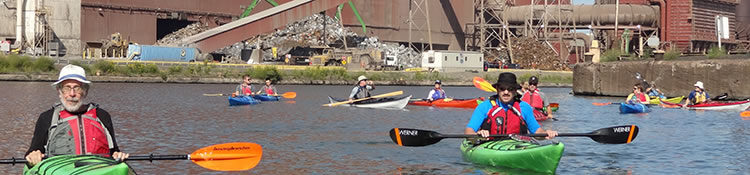Many kayakers enjoying the Rouge River Water Trail in front of a manufacturing facilty