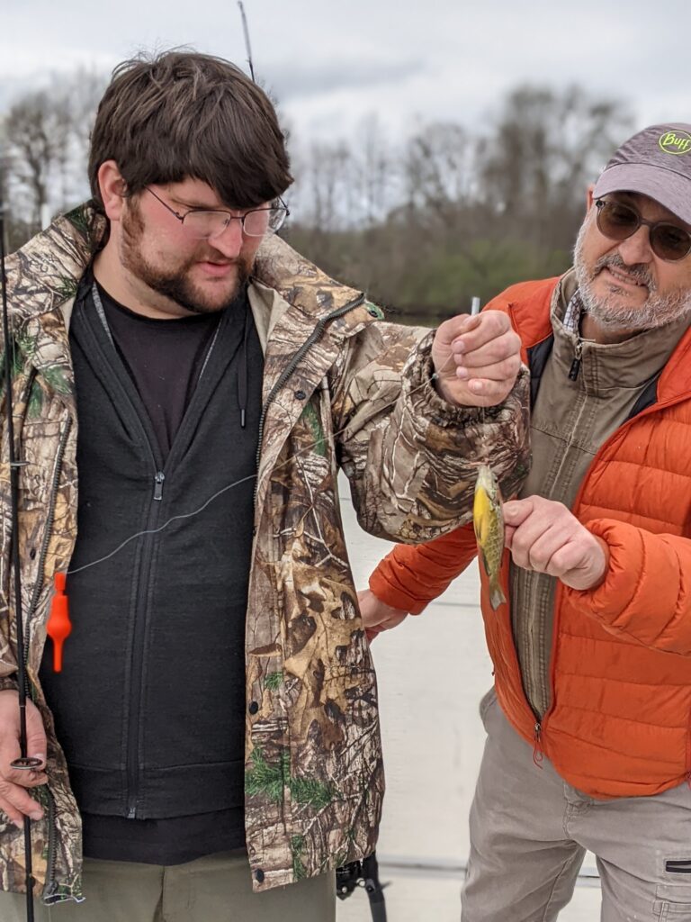 Two men observing a fish they caught in the river